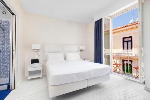 a white bedroom with a bed and a window at Palazzo Tasso in Sorrento
