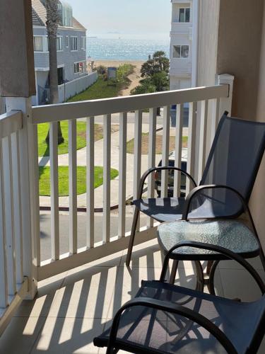 a patio area with chairs, tables, and a balcony at Ocean Surf Inn & Suites in Huntington Beach