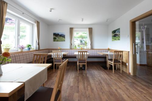 un ristorante con tavoli e sedie in legno e finestre di Garni Pircher a Tirolo