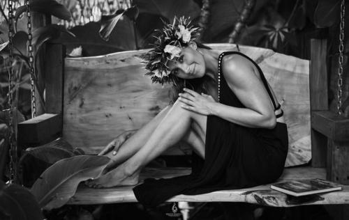 a woman sitting on a swing wearing a flower crown at Hare Nua Hotel Boutique in Hanga Roa