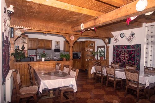 comedor con mesas y sillas y cocina en Pensiunea Bontos en Budeşti