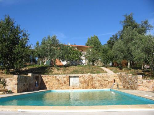 a swimming pool in front of a stone wall at Quinta no Pinhal in Vila Nova de Poiares