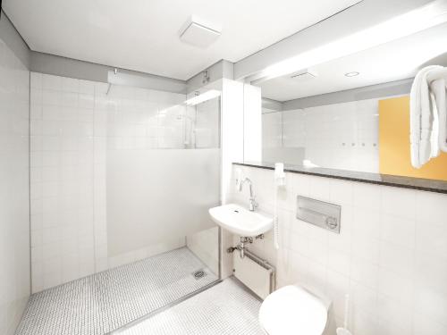 een witte badkamer met een wastafel en een toilet bij Bildungs- und Tagungshaus Haus Neuland in Bielefeld
