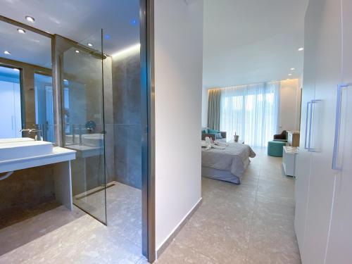 a bathroom with a shower and a bed and a sink at Lardos Bay Hotel in Lartos