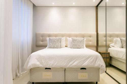 1 dormitorio con 1 cama grande con sábanas y almohadas blancas en Studio Excelente no Pátio Milano #CA03, en Florianópolis