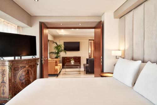 
a hotel room with a bed and a television at Bellevue On The Beach Suites in Rhodes Town
