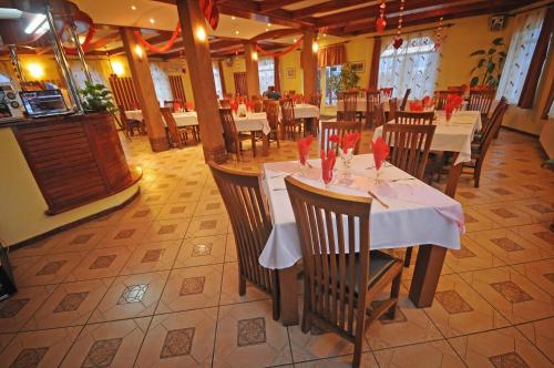 uma sala de jantar com mesas e cadeiras num restaurante em Imola Motel em Gheorgheni