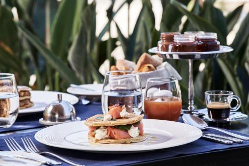 a table with a sandwich on a white plate at Bellevue On The Beach Suites in Rhodes Town