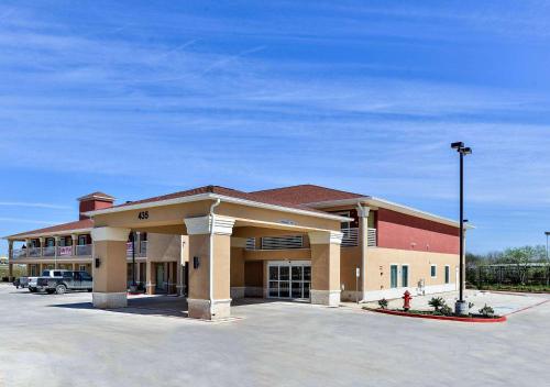 a large building with a parking lot in front of it at Scottish Inn & Suites Cotulla, TX in Cotulla