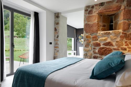 a bedroom with a bed and a stone wall at Oribar Casa Rural in Aia