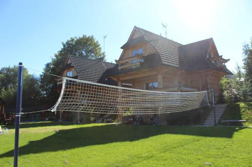 a large wooden house with a net in the yard at Domki w Białce pod Basenami, 50 m od term i wyciągów in Białka Tatrzanska
