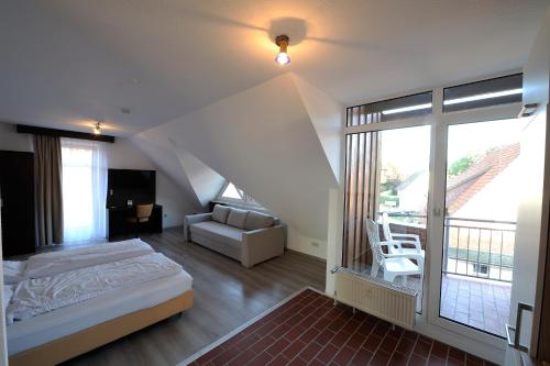 ein Schlafzimmer mit einem Bett und einem Sofa sowie einem Balkon in der Unterkunft Hotel zur Post in Steimbke