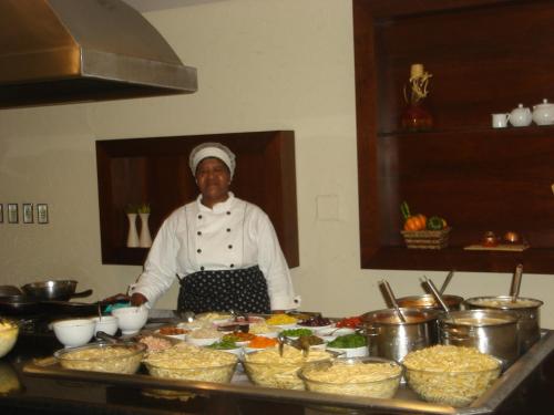 a chef standing in front of a table of food at Mara Turismo Hotel in Catalão