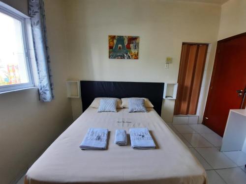 Un dormitorio con una cama grande con dos toallas encima. en Hotel Três Passos - Prox ao Aeroporto e Rodoviária, en Porto Alegre