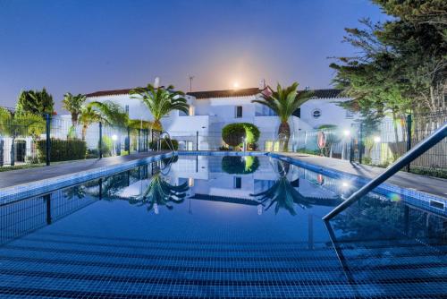 una piscina frente a un edificio por la noche en Villas Flamenco Beach Conil en Conil de la Frontera