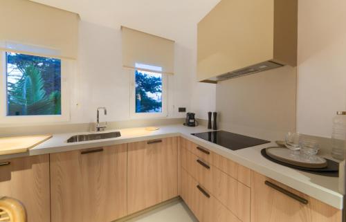 a kitchen with wooden cabinets and a sink and a window at Villas Flamenco Beach Conil in Conil de la Frontera