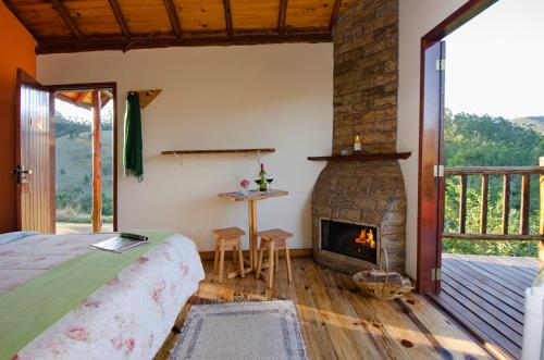a bedroom with a fireplace and a bed and a table at Pousada Lua de Minas in Visconde De Maua