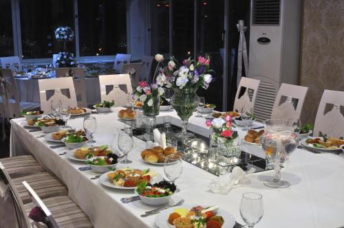 a long table with plates of food and flowers on it at Grand Atakum Hotel in Samsun