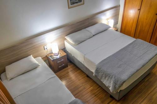 een slaapkamer met een bed en een nachtkastje met 2 lampen bij Hotel Portucali in Ribeirão Preto