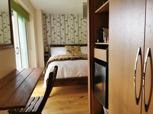 um pequeno quarto com uma cama e uma mesa de madeira em The Base Vegan Retreat Animal Sanctuary em Bristol