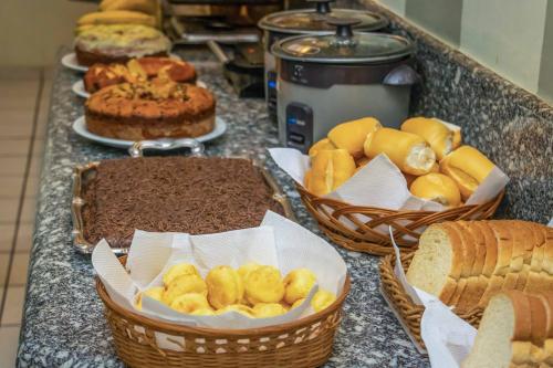 a counter topped with baskets of bread and pastries at Hotel Portucali in Ribeirão Preto