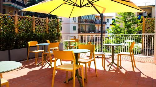 a patio with tables and chairs and a yellow umbrella at Relais Villa Montedonzelli in Naples
