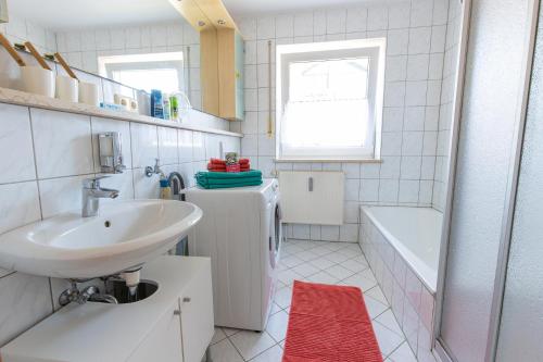 a white bathroom with a sink and a tub at Ferienwohnung Burgkirchen in Unterneukirchen
