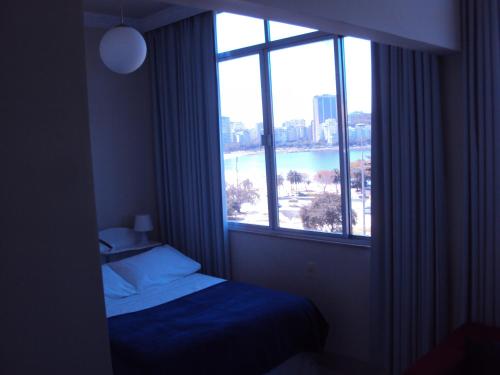- une chambre avec un lit et une grande fenêtre dans l'établissement Apartamento Botafogo Beach, à Rio de Janeiro