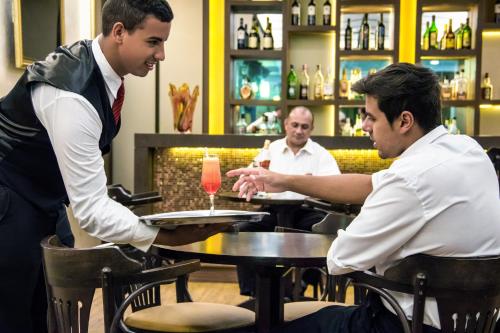 two men sitting at a table in a bar at Hotel Nacional Inn Poços de Caldas - Lazer completo e Gastronomia no Centro in Poços de Caldas