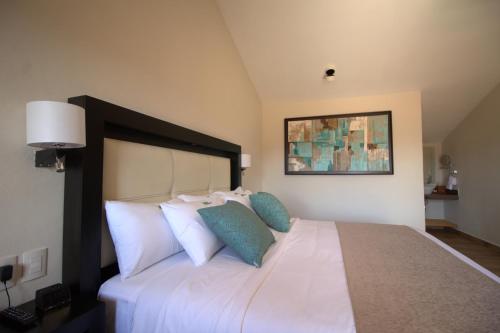 a bedroom with a large white bed with blue pillows at Hotel Villa Murano in San Cristóbal de Las Casas