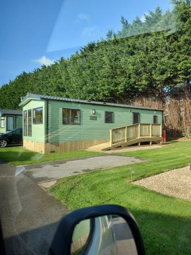 a green house with a porch and a deck at Rustling Pines at Knaresborough Lido in Harrogate