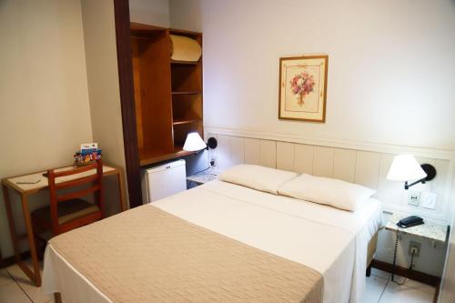 Habitación pequeña con cama, mesa y escritorio. en Hotel BH Palace, en Belo Horizonte