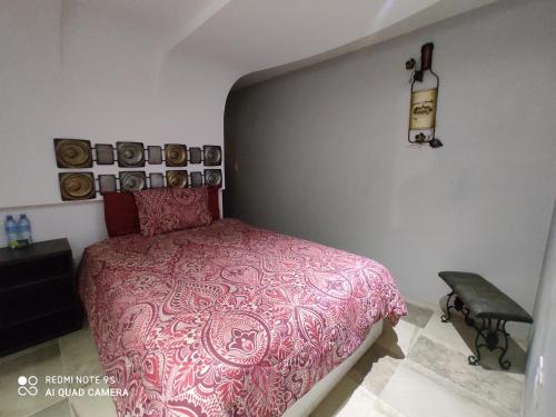 a bedroom with a pink bed and a black chair at La Vid Posada Inn in Valle de Guadalupe