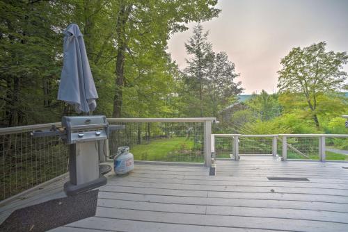 a patio with an umbrella and a grill on a deck at Cozy Stockbridge Cabin - Walk to Beach and Lake! in Stockbridge