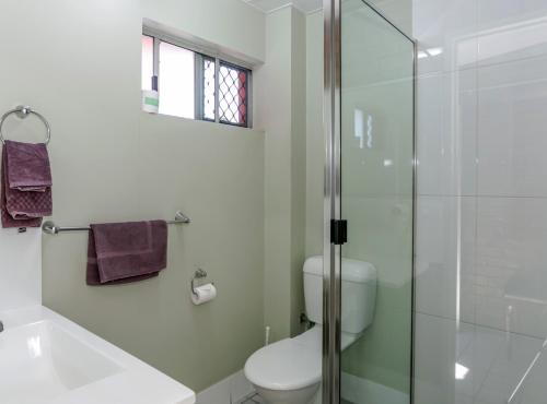 a bathroom with a toilet and a glass shower at Matilda Motel in Bundaberg