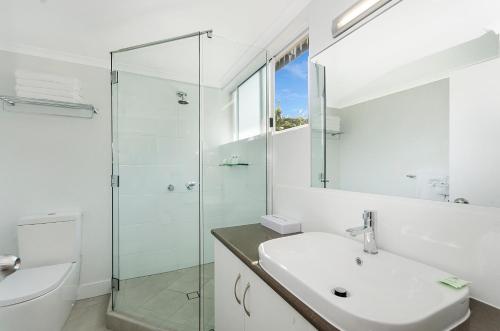 ein Bad mit einem Waschbecken und einer Glasdusche in der Unterkunft By The Sea Port Douglas in Port Douglas