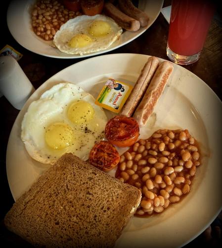two plates of eggs and bread and beans on a table at Royal Mansion in Kulu