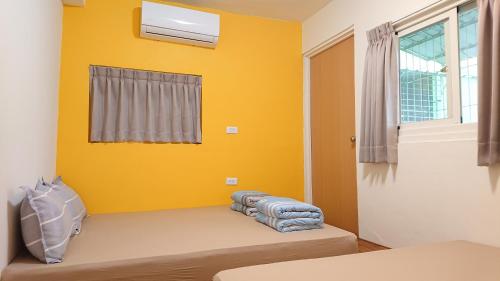 a room with a yellow wall and a bed at 光華民宿 in Chaozhou