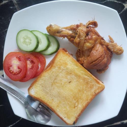 a plate of food with chicken and toast and vegetables at Watukarung Sackstone Guesthouse in Kalak
