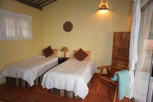 una camera con due letti e una sedia e una finestra di Highcroft Retreat & Lodge a Umzumbe