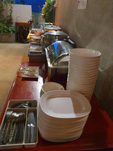 een buffet met witte borden en keukengerei bij River Hill Side Resort in Ban Tha Thong Mon