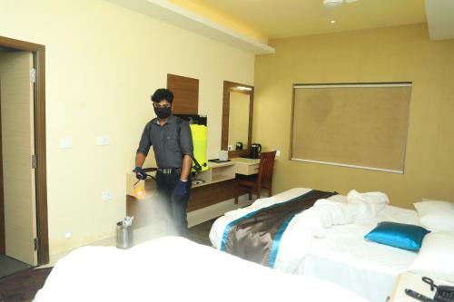 a man wearing a mask in a room with two beds at Laya Regency in Mayiladuthurai