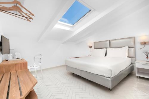 a white bedroom with a bed and a television at Palazzo Tasso in Sorrento