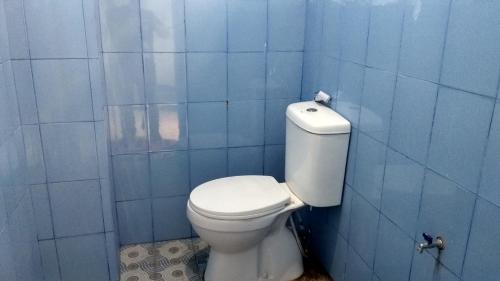 baño con aseo en una pared de azulejos azules en OYO 90001 Homestay 47 Latanete, en Makassar