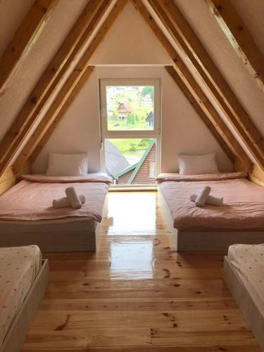 two beds in a attic room with a window at Guest House Tamara in Žabljak