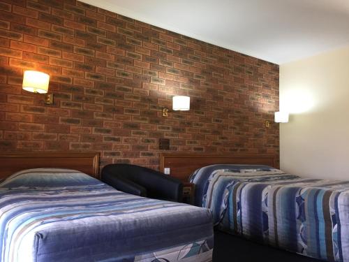 a room with two beds and a brick wall at The Finley Palm Motor Inn in Finley