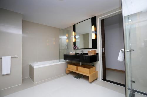 a bathroom with a tub and a sink and a mirror at Asdal Gulf Inn Boutique Hotel- SEEF in Manama