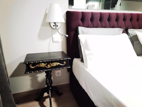 a bed with a table with a lamp on it at Downtown Loulé in Loulé