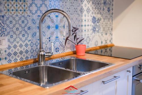 eine Spüle aus Edelstahl in einer Küche mit blauen und weißen Fliesen in der Unterkunft Casa stellata Napoli home in the center in Neapel