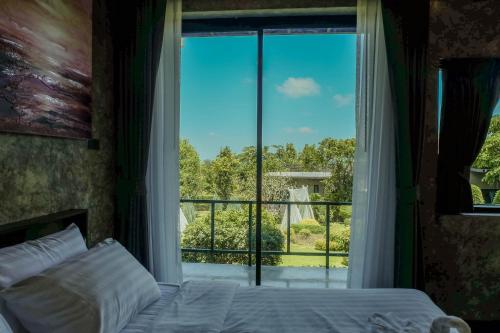 a bedroom with a bed and a large window at Phuwadee Resort Khao Yai in Nong Sarai